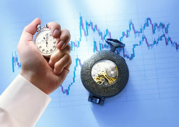 Candlestick chart, watch and stopwatch in male hand