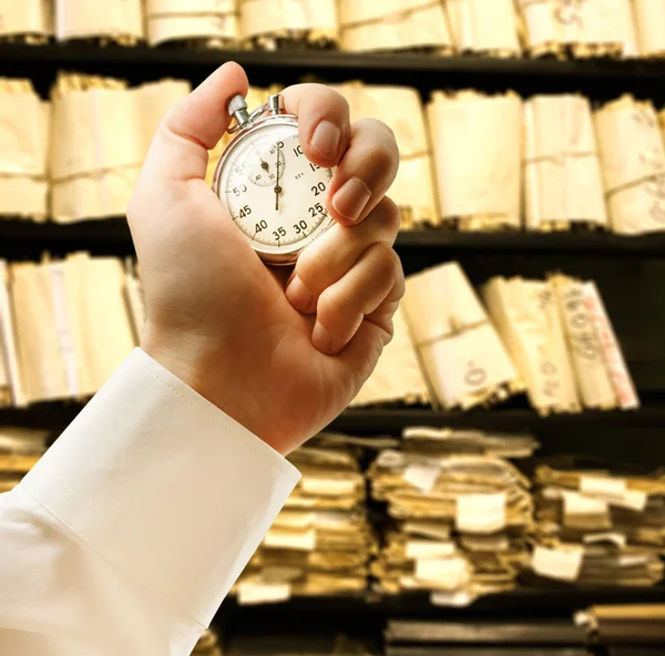Paper documents stacked archive and stopwatch in hand — Stock Photo, Image