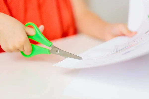 Ruce dítěte řezání papíru s nůžkami — Stock fotografie