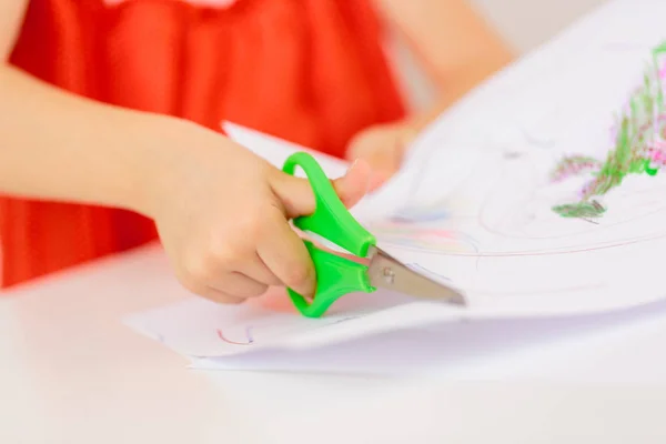 Le mani del bambino tagliano la carta con le forbici — Foto Stock