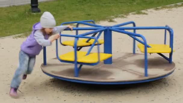 Маленькая девочка играет на карусели — стоковое видео