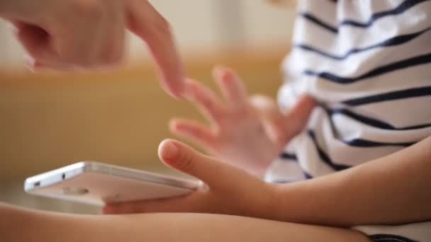 Маленькая девочка играет со смартфоном — стоковое видео