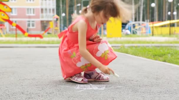 Niña dibujando con tiza sobre asfalto al aire libre — Vídeo de stock