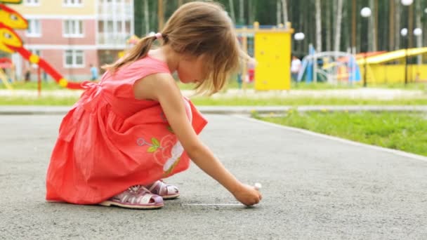 Niña dibujando con tiza sobre asfalto al aire libre — Vídeos de Stock