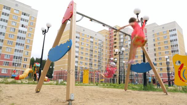 Dos niñas pequeñas balanceándose en swing al aire libre — Vídeo de stock