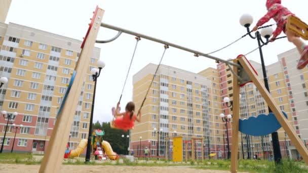 Twee kleine meisjes swingen op schommel outdoor — Stockvideo