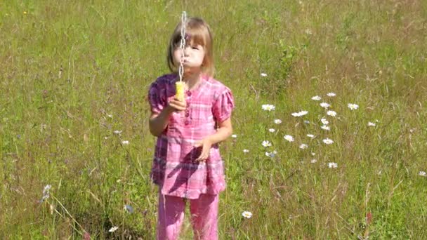 Bulles de savon enfant soufflant sur le champ de camomille le matin d'été — Video