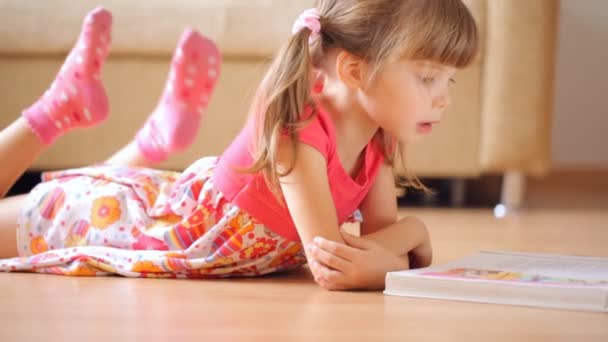 Mała Dziewczynka Czyta Książkę Leżąc Podłodze — Wideo stockowe