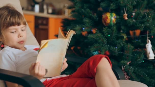 Niña Leyendo Libro Delante Del Árbol Navidad — Vídeo de stock
