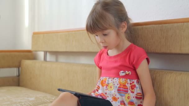 Маленька Дівчинка Читає Електронну Книгу Дивані — стокове відео
