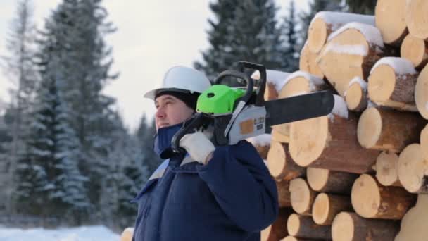 Werknemer Met Kettingzaag Tegen Stapel Van Logboeken — Stockvideo