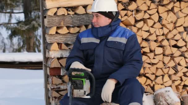 Werknemer Met Kettingzaag Tegen Stapel Van Logboeken — Stockvideo