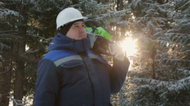 İşçi kış ormanda etrafa omuz chainsaw ile