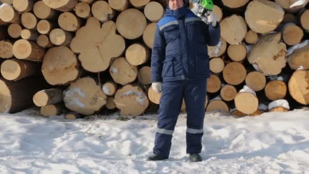 Arbeiter Mit Kettensäge Gegen Holzstapel — Stockvideo