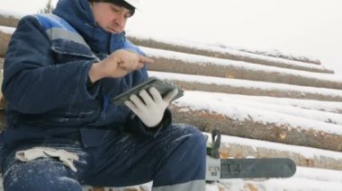 İşçi ile büyük kış orman günlüklerinde yığını tablet bilgisayarda