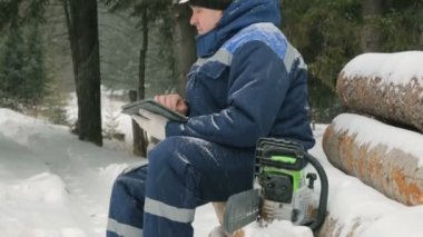 İşçi ile büyük kış orman günlüklerinde yığını tablet bilgisayarda