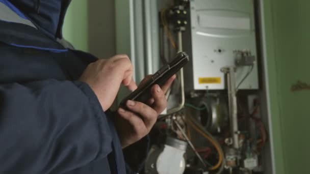 Worker typing on smartphone against gas-fire boiler — Stock Footage Worker Typing Smartphone Gas Fire Boiler Video Clip