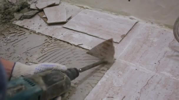 Munkás eltávolítása régi csempe a padlóról a fürdőszobában — Stock videók