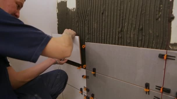 Travailleur pose de tuiles sur le mur — Video