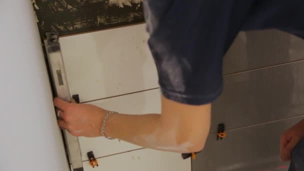 Εργάτης ελέγχει επίπεδα πλακιδίων τοποθέτησης στον τοίχο — Αρχείο Βίντεο
