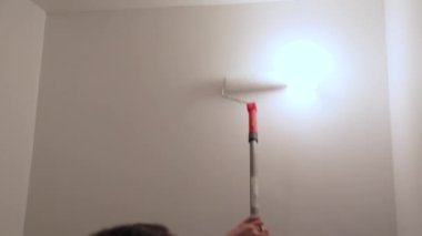 İşçi duvarları beyaz boyayla boyuyor.