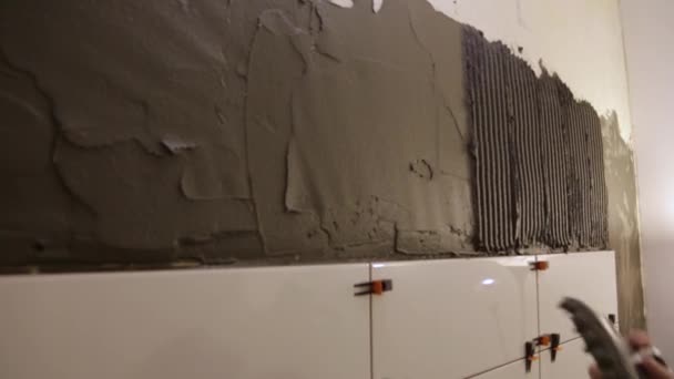 Працівник кладе клей для плитки на стіну — стокове відео