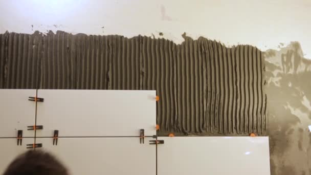 Рабочий кладет плитку на стену — стоковое видео