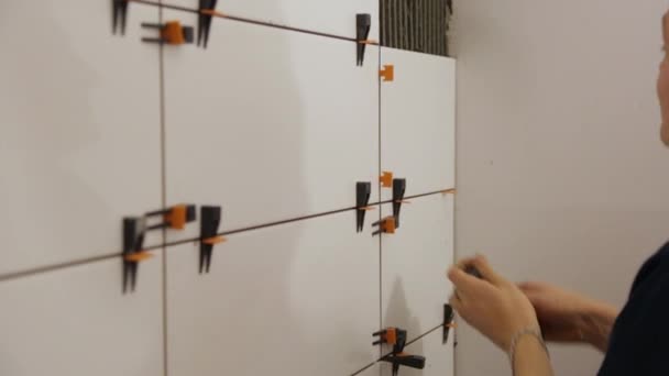 Працівник кладе плитку на стіну — стокове відео