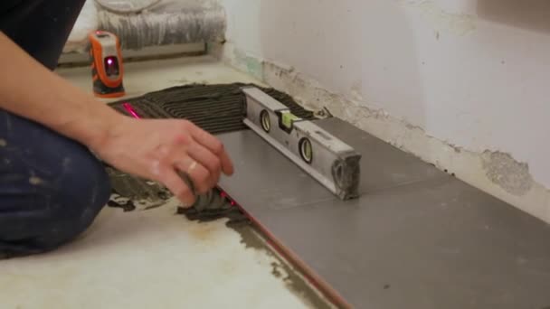 Worker checking level laying tiles on the floor — Stock Video