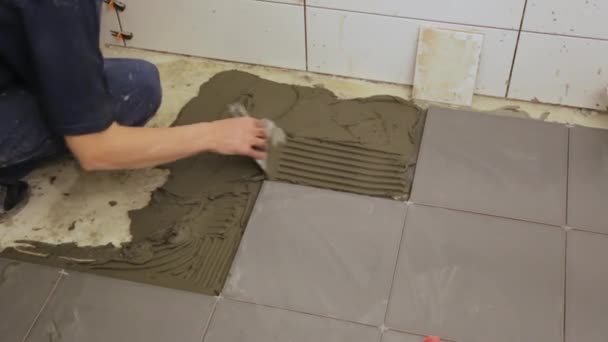 Εργαζόμενος βάζοντας κόλλα πλακιδίων στο πάτωμα — Αρχείο Βίντεο