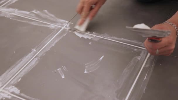 바닥에 있는 타일들 사이를 연결시키는 작업을 하는 사람 — 비디오