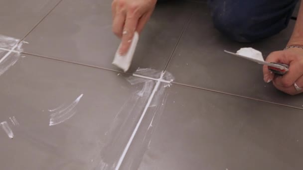 Рабочий высечка швов между плитками на полу — стоковое видео