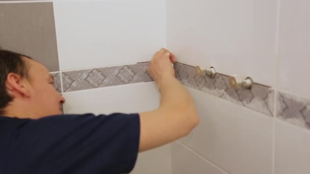 Рабочий лопасти швы между плитками на стене — стоковое видео
