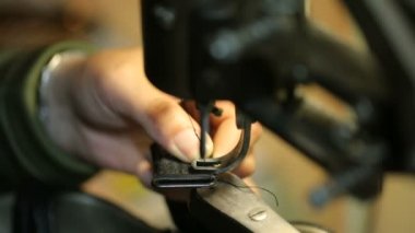 Ayakkabıcı dikiş makinesine dikiş dikiyor. Yakın çekim.