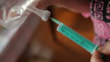 Kadın dolu bir şırınga alıyor.