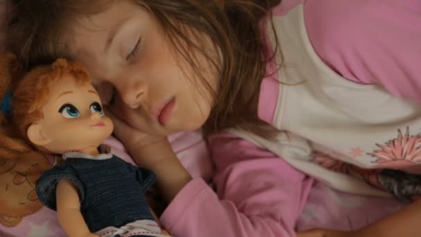 Little girl sleeping with her doll in morning light — Stock Video