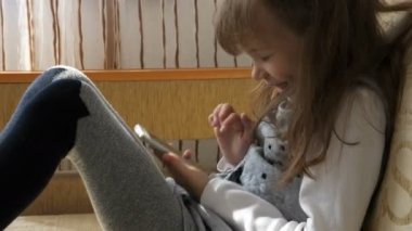 Kanepede akıllı telefonu olan küçük kız.