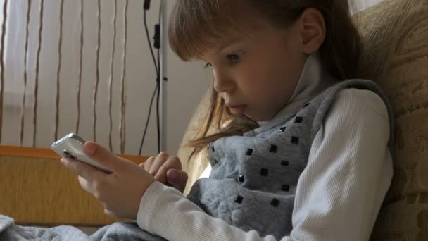 Petite fille avec smartphone sur canapé — Video
