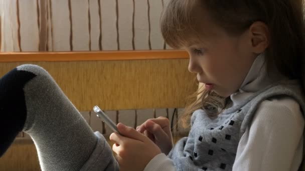 Petite fille avec smartphone sur canapé — Video