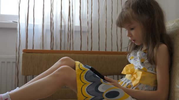 Menina lendo livro eletrônico no sofá — Vídeo de Stock