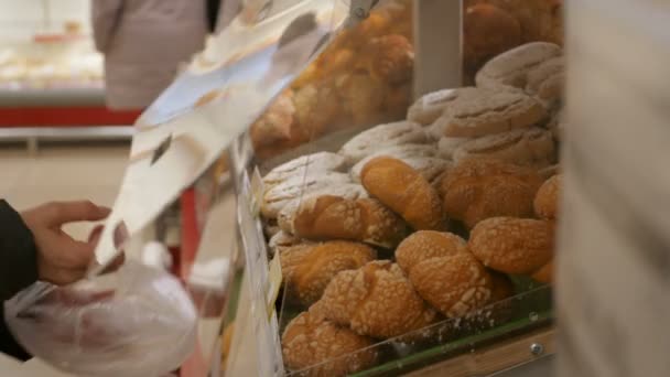 Женщина берет булочки в продуктовом магазине — стоковое видео