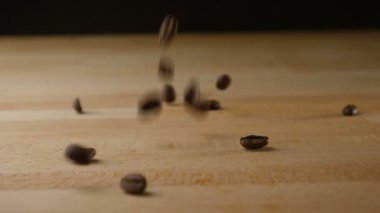 Kahve çekirdekleri masaya ağır çekimde düşüyor.