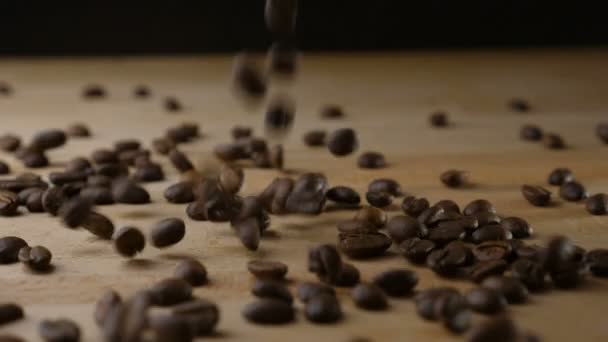Koffiebonen vallen op een tafel in slow motion — Stockvideo