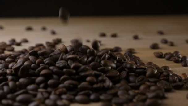 Granos de café cayendo sobre una mesa en cámara lenta — Vídeos de Stock