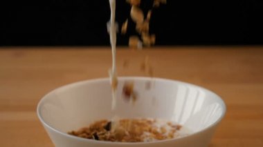 Müsli ve süt bir kaseye dökülüyor.