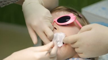 Dişçi koltuğundaki küçük kız dişini tedavi ettiriyor.