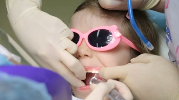 Mała dziewczynka na fotelu dentystycznym, która leczy zęby. — Wideo stockowe