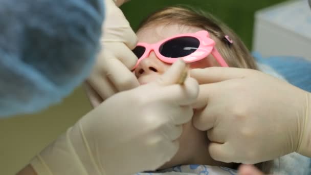 Маленька дівчинка в стоматологічному кріслі лікує зуб — стокове відео