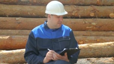 Defterli işçiler kütüklerin üzerinde oturuyor