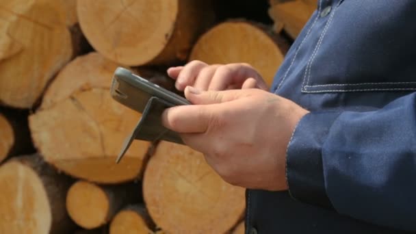 Werkman met tablet PC tegen stapel logs — Stockvideo